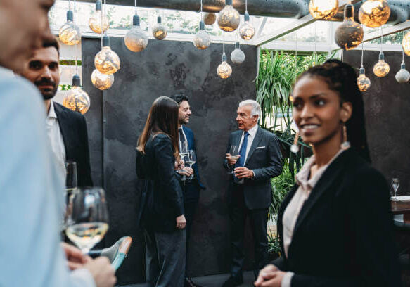 Elegant people are talking together in an high-end restaurant during the aperitif. Business meeting outside the office.